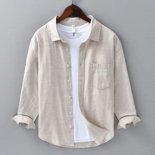 Beige shirt over a white t-shirt on a hanger against a gray background